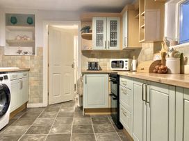 A kitchen with cabinets and appliances at Waterfall Cottage in Dyserth