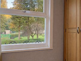 A window view showing trees and a garden at Waterfall Cottage in Dyserth