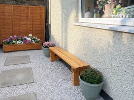 An outdoor area with a wooden bench and flower beds at Waterfall Cottage in Dyserth
