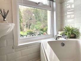 A bathroom with a bathtub and sink overlooking a garden at Waterfall Cottage Dyserth