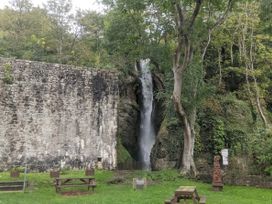 A waterfall beside a stone wall in a park at Waterfall Cottage Dyserth
