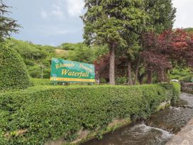An outdoor area with a sign and trees at Waterfall Cottage in Dyserth