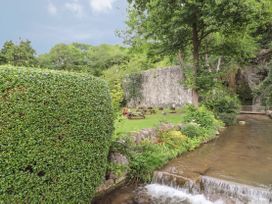 A garden with a river and picnic tables at Waterfall Cottage in Dyserth