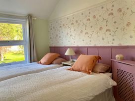 A bedroom with two beds and a window overlooking a garden at Waterfall Cottage in Dyserth
