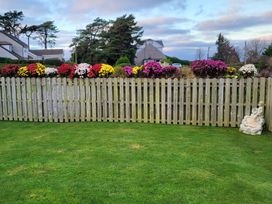 A garden with a wooden fence topped with flowers at Top Of The Lane Luxury Holiday Apartment in Benllech