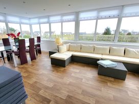 A conservatory with a dining table and chairs and a sofa at Top Of The Lane Luxury Holiday Apartment, Benllech