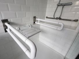 A shower area with grab bars and a shower seat at Top Of The Lane Luxury Holiday Apartment in Benllech