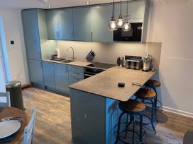 A kitchen with cabinets, sink, stove, and bar stools at 51 Fernhill Heights Charmouth