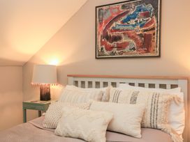 A bedroom with a bed, pillows, lamp, and painting at Pudding Hill Barn Cottage Bibury