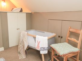 A nursery with a crib and a chair at Pudding Hill Barn Cottage Bibury