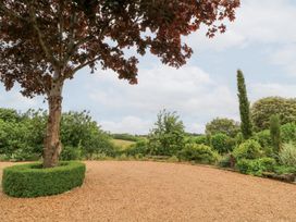 A garden with a tree and lush greenery at Pudding Hill Barn Cottage Bibury