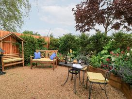 A garden with a bench and table surrounded by plants at Pudding Hill Barn Cottage, Bibury