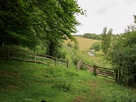A pathway through trees with a gate and fence at Pudding Hill Barn Cottage Bibury