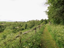 A path beside a fence leading through grass and trees at Pudding Hill Barn Cottage Bibury