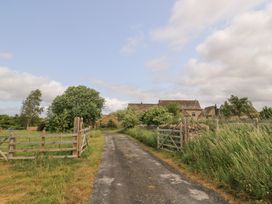 A dirt road leading to a house with trees at Pudding Hill Barn Cottage Bibury