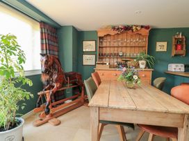 A dining room with a table and rocking horse at Pudding Hill Barn Cottage Bibury