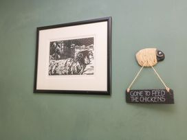 A framed artwork and a sheep decoration on a wall at Pudding Hill Barn Cottage Bibury