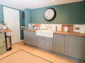 A kitchen with a sink and clock at Pudding Hill Barn Cottage in Bibury