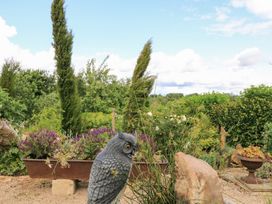 A garden with an owl statue and flowers at Pudding Hill Barn Cottage Bibury