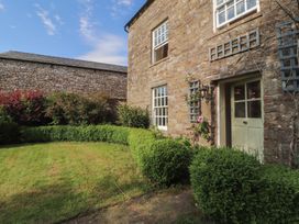A garden with a stone house and bushes at Garsdale Foot in Sedbergh