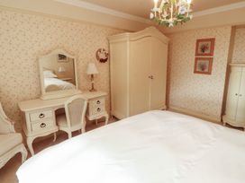 A bedroom with a bed, wardrobe, and dressing table at Garsdale Foot in Sedbergh