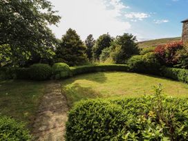 A garden with bushes and a pathway at Garsdale Foot in Sedbergh