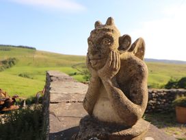 A statue on a stone wall overlooking a grassy landscape at Garsdale Foot in Sedbergh