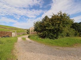 A gravel road with stone walls and trees at Garsdale Foot in Sedbergh