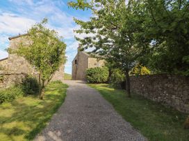 A pathway lined with trees and stone buildings at Garsdale Foot in Sedbergh