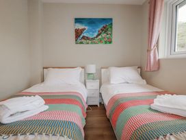 A bedroom with two single beds and a painting at Kippy Cottage in Porthtowan