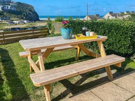 A table with benches and a plant pot at Kippy Cottage in Porthtowan