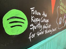 A wall with Spotify logo and text about a playlist at Kippy Cottage in Porthtowan