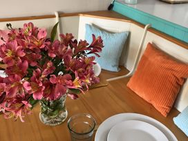 A dining room with a flower vase and plates at Kippy Cottage Porthtowan