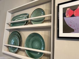 A shelf with plates and artwork at Kippy Cottage, Porthtowan