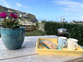 A table with a flower pot, coffee, and snacks at Kippy Cottage in Porthtowan