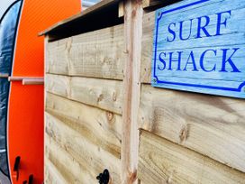 A surf shack with a wooden structure and a surfboard at Kippy Cottage Porthtowan