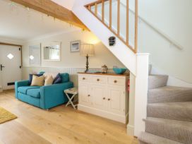 A living room with a blue sofa cushions cabinet and stairs at Herbies Cottage in Snettisham