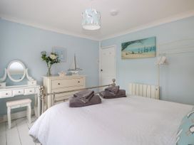 A bedroom with a bed with towels on it a white dresser with flowers and a sailboat and a dressing table at Herbies Cottage in Snettisham