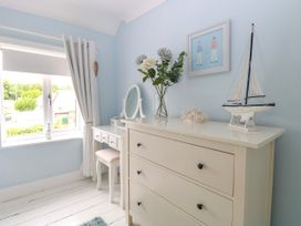 A bedroom corner with a white dresser and vanity table near a window with white curtains at Herbies Cottage in Snettisham