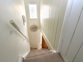 A carpeted staircase with a white handrail and a round mirror on the wall at Herbies Cottage in Snettisham