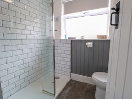 A bathroom with a glass shower enclosure and a toilet next to a window at Herbies Cottage in Snettisham