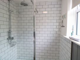 A bathroom with a walk-in shower with white subway tiles and a window with a rolled towel on the sill at Herbies Cottage in Snettisham