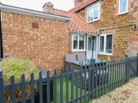 A fenced outdoor patio area with a table and chairs next to a brick and stone house
