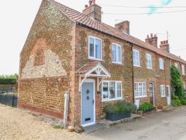 A row of brick and stone cottages with tile roofs and white framed windows on a street at Herbies Cottage in Snettisham