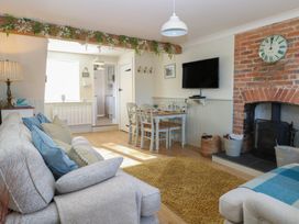 A living room with a sofa, table, and television at Herbies Cottage Snettisham