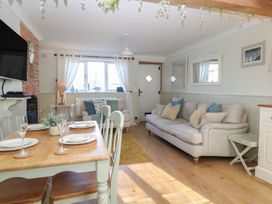 A living room with a dining area and sofa at Herbies Cottage in Snettisham