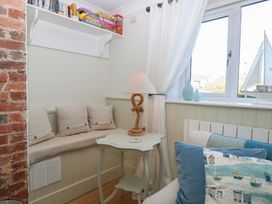 A snug with a seating area and shelf for games at Herbies Cottage in Snettisham