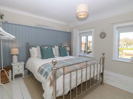 A bedroom with a bed and windows at Herbies Cottage Snettisham
