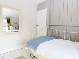 A bedroom with a bed and mirror at Herbies Cottage in Snettisham