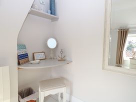 A dressing area with a mirror and shelf at Herbies Cottage in Snettisham